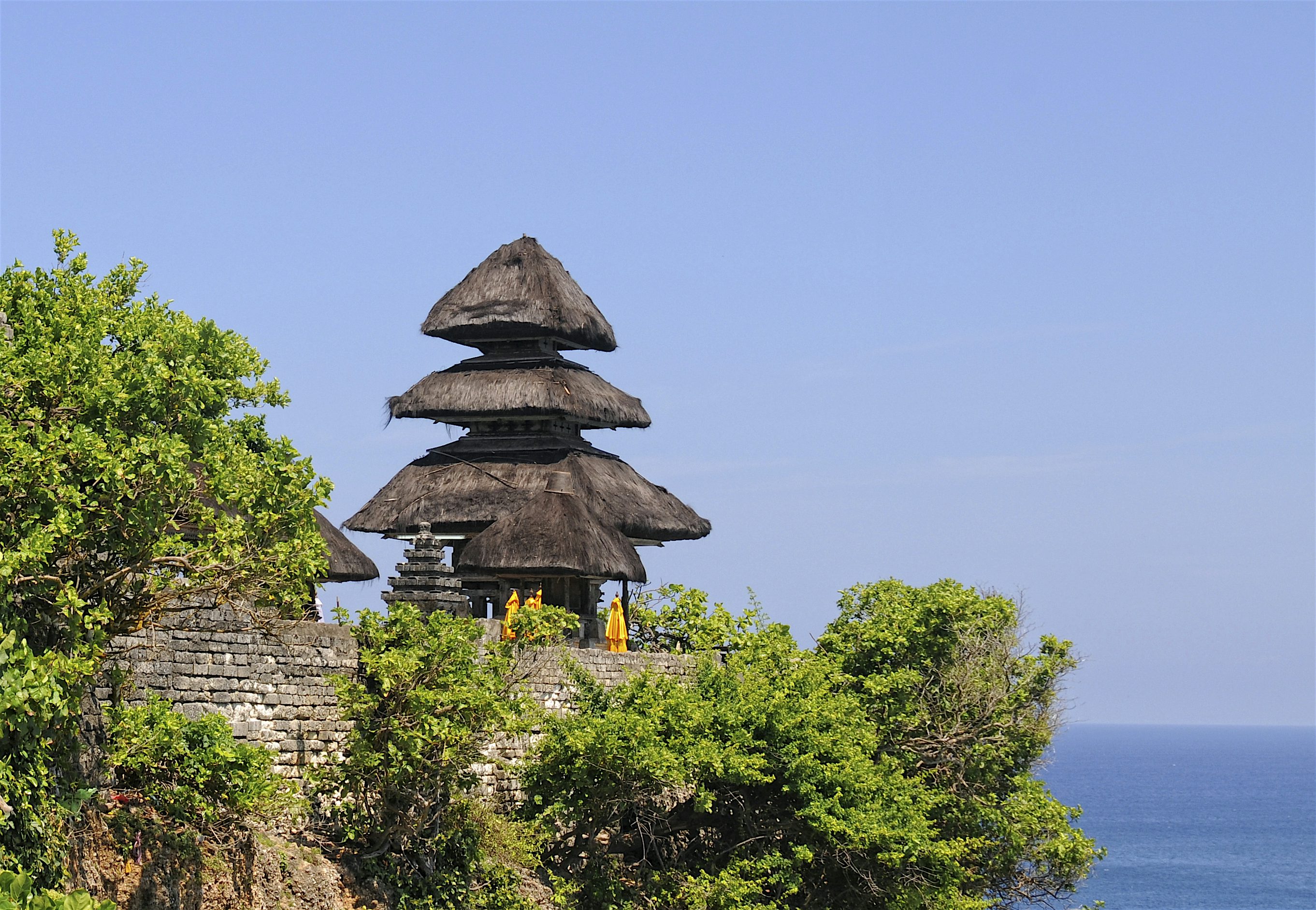 Uluwatu-temppeli vehreän kasvillisuuden keskellä kallion reunalla