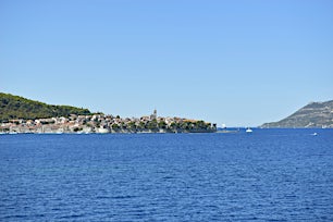 Sininen meri ja taivas, taustalla kaupunki ja vuoria.