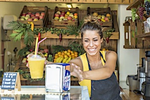 Iloinen nainen smoothie-kioskilla tai hedelmämyymälässä