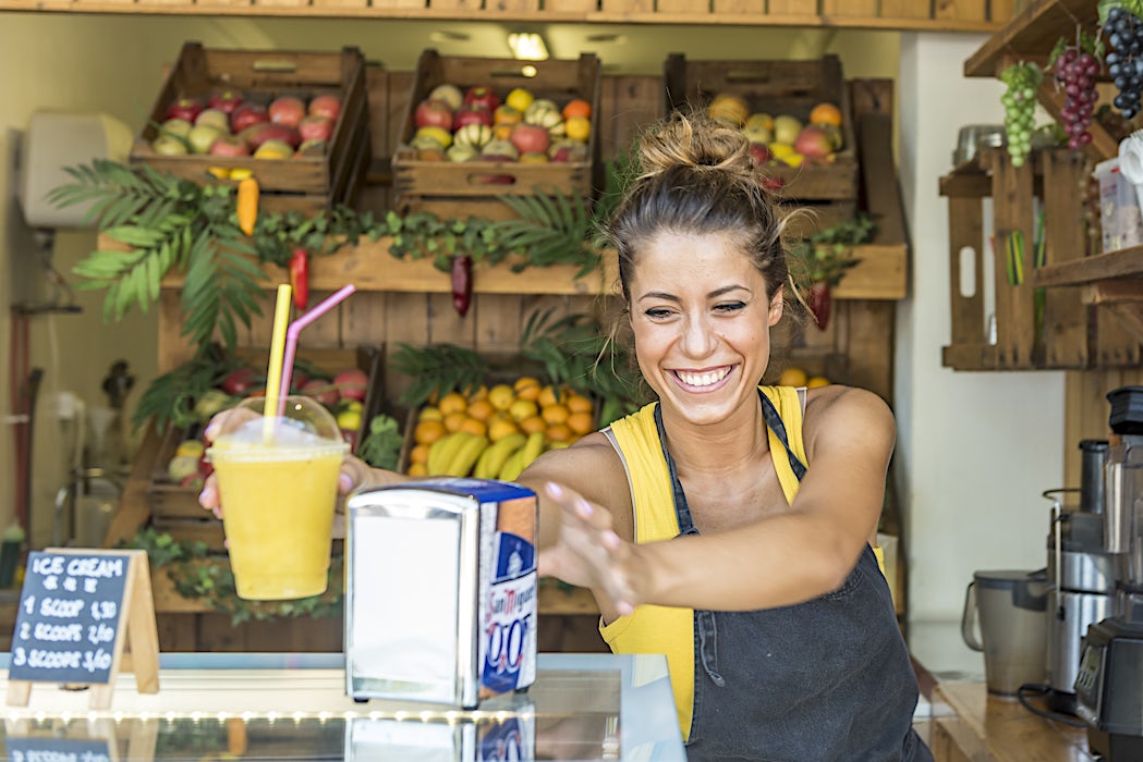 Iloinen nainen smoothie-kioskilla tai hedelmämyymälässä