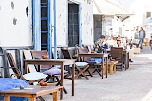 Ravintola kadun varrella, puisia tuoleja ja valkoisia seiniä