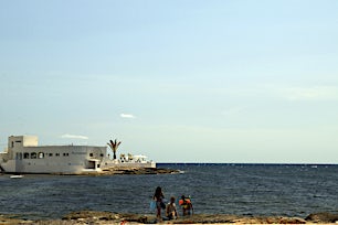 Rakennus taustalla ja ihmisiä rannalla katselemassa