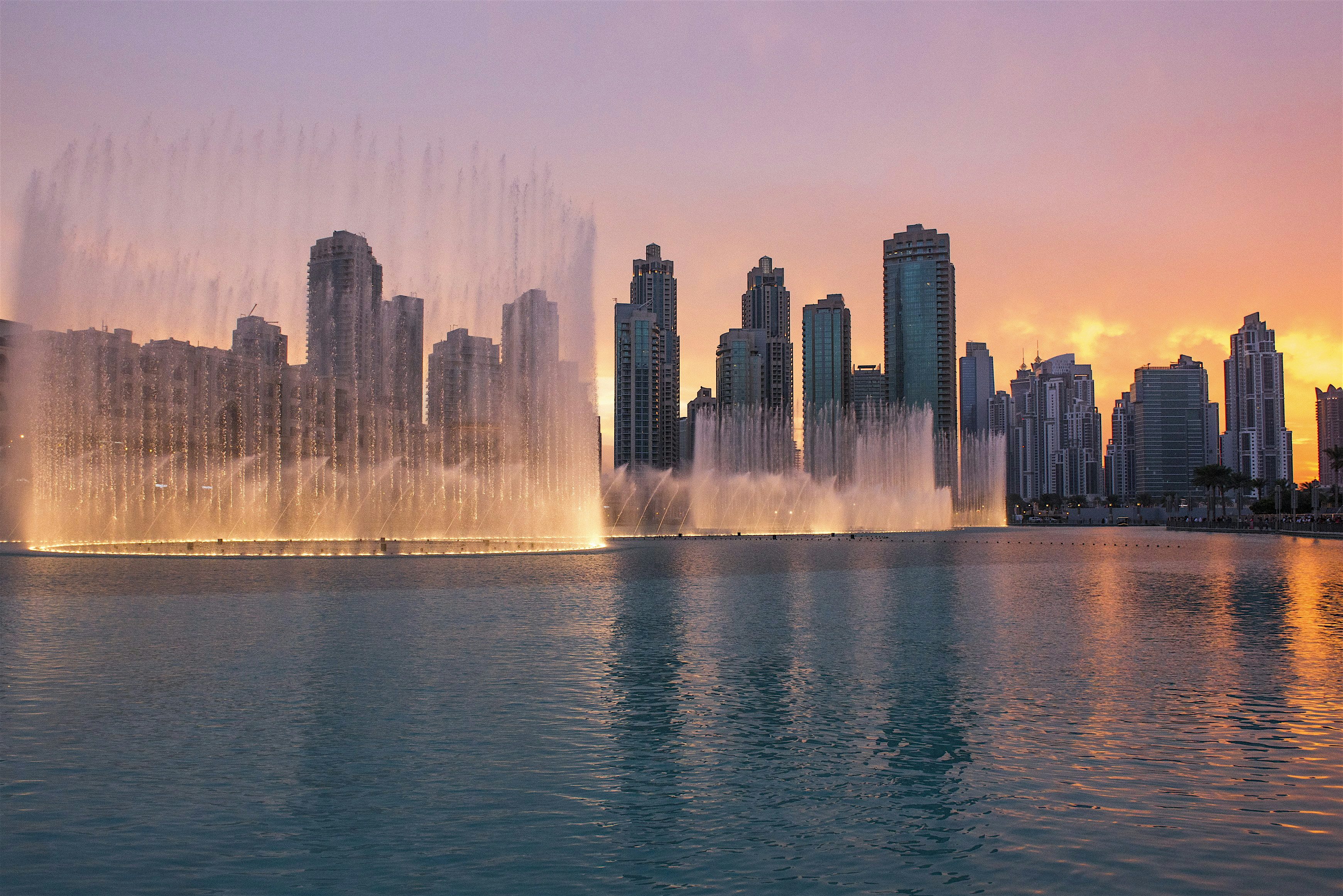 Dubai Fountain -suihkulähde-esitys auringonlaskun aikaan pilvenpiirtäjien edustalla