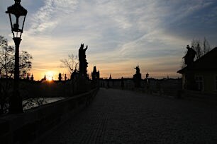 Auringonlasku pimeässä illassa, kuvassa patsaiden varjoja ja taivas.