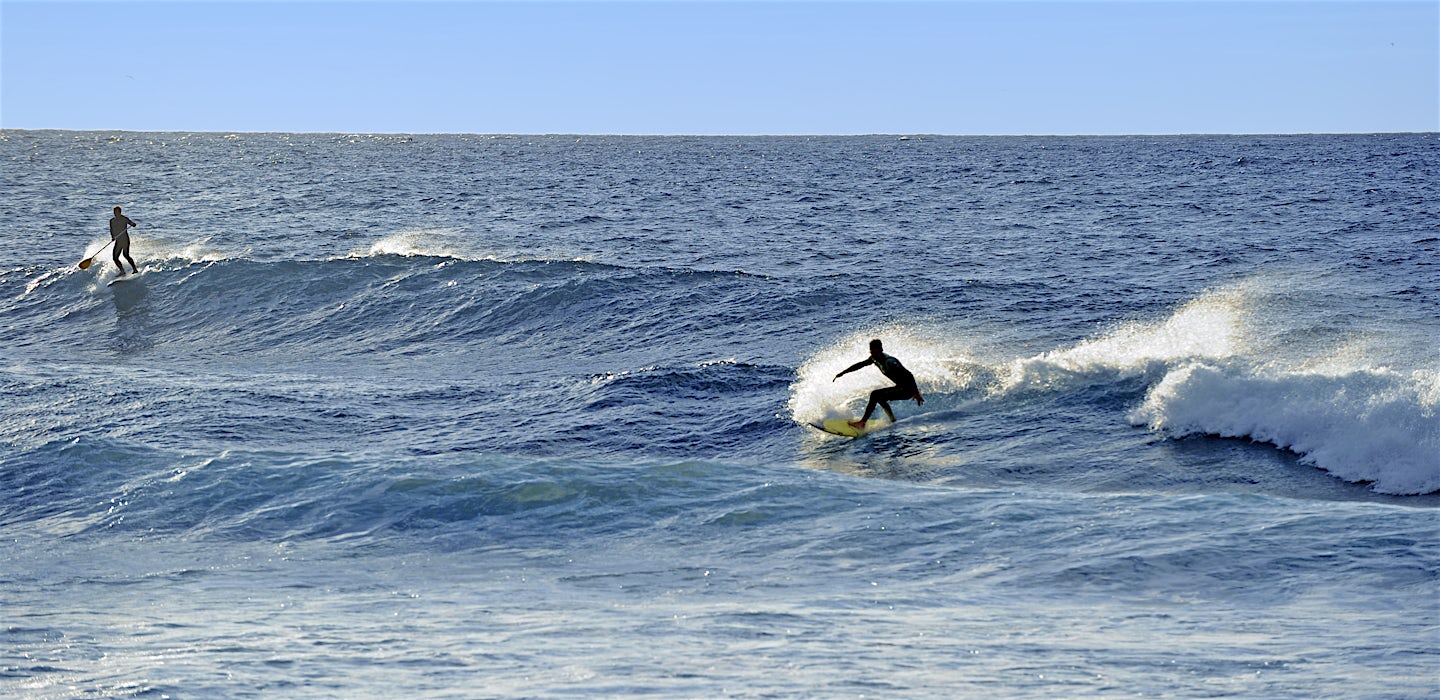 Surffaajia ratsastamassa aalloilla sinisessä meressä
