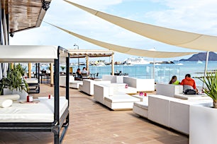 Ulkolounge valkoisilla sohvilla meren rannalla