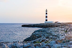Majakka kallioisella rannalla meren ääressä ilta-auringossa