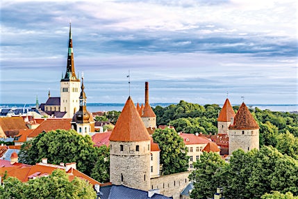 Vanhankaupungin punatiilisiä kattoja, pyöreitä torneja ja kirkkoja. Taustalla meri ja sininen taivas.