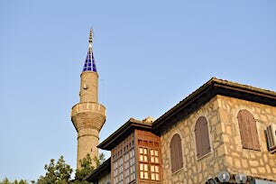 Historiallinen kivitalo ja minareetti sinistä taivasta vasten.