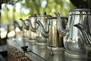 Kiiltäviä metallisia teepannuja rivissä perinteisessä teehuoneessa.
