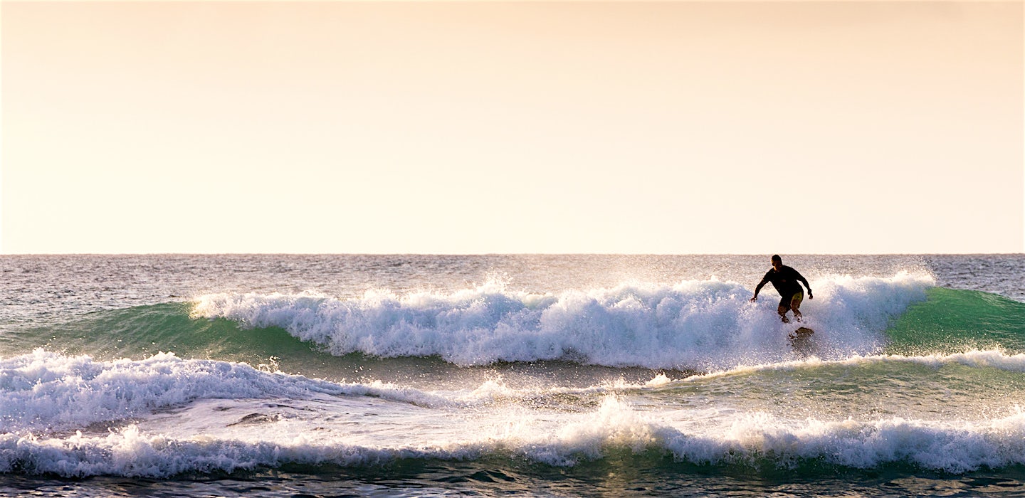 Surffaaja aallolla auringonlaskussa