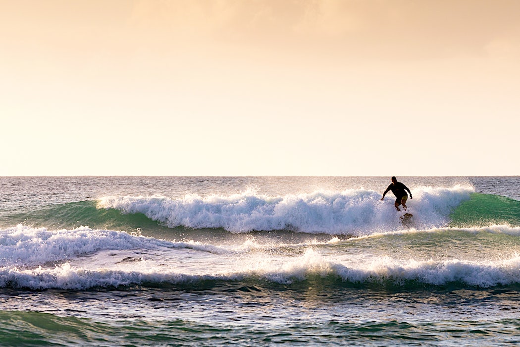 Surffaaja aallolla auringonlaskussa