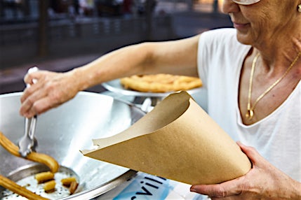 Henkilö laittaa churroja paperitötteröön.