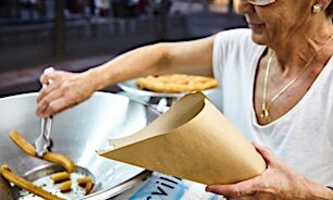 Henkilö laittaa churroja paperitötteröön.