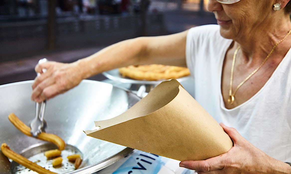 Henkilö laittaa churroja paperitötteröön.