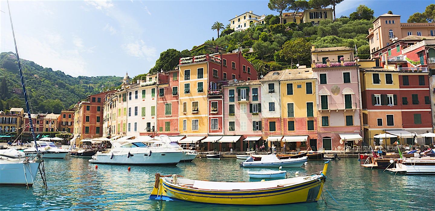 Värikkäiden talojen ja vehreiden kukkuloiden reunustama venesatama Portofinossa, Liguriassa.